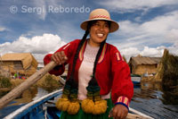 Una mujer vestida con trajes típicos regionales navega con su barca entre las islas de los Uros. 